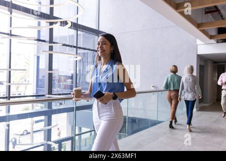 Eine Frau mittleren Alters, die mit der Rasse läuft, Kaffee hält Stockfoto