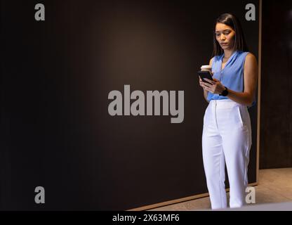 Eine birassische Frau mittleren Alters, die ein Smartphone im Büro hält, Kopierraum Stockfoto