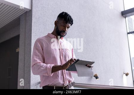 Ein Afroamerikaner mittleren Alters liest von einem Tablet im Büro Stockfoto