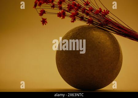 Stillleben mit einem Blumenstrauß aus roten getrockneten Wildblumen auf dekorativer Kugel auf gelbem Hintergrund. Künstlerische Blumenkomposition. Ländliche Blumen. Kopierbereich. Stockfoto