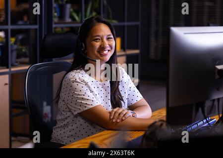 Birassische Geschäftsfrau auf dem Bildschirm mit Headset-Bewertungen, die spät im Büro arbeitet Stockfoto