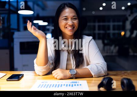 Im Büro lacht eine birassische Geschäftsfrau während eines Videoanrufs Stockfoto