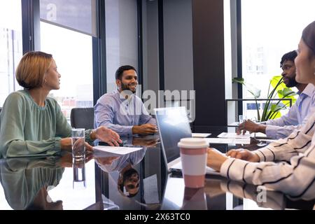 Ein vielseitiges Team, das im Büro über Geschäftspapiere diskutiert Stockfoto