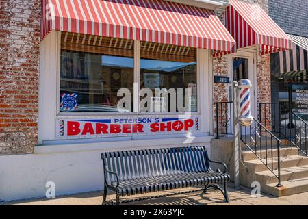 Princeton, IL, USA-28. Februar 2024: Vordereingang zum altmodischen, kleinen Stadtfriseur mit hellrot gestreiftem Markise und klassischer Friseurstange. Stockfoto