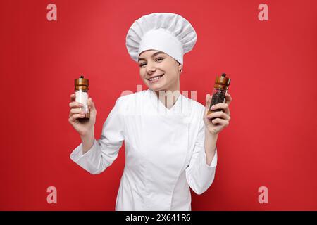 Professioneller Koch mit Salz- und Pfefferstreuer auf rotem Hintergrund Stockfoto