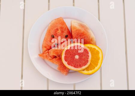 In Scheiben geschnittene Wassermelonen und Zitrusfrüchte auf einer weißen Platte Stockfoto