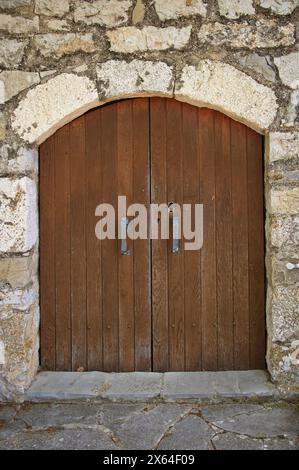 Alte Holztür mit Bogen auf Steinhaus Stockfoto