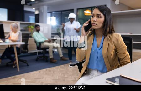 Ein vielseitiges Büroteam aus kaukasischen und afroamerikanischen Frauen, die am Telefon chatten Stockfoto