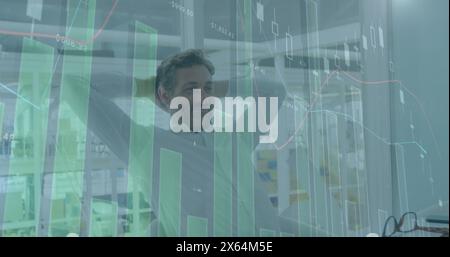 Bild mehrerer Diagramme, wechselnde Zahlen, müder kaukasischer Mann dehnt sich nach Abschluss der Arbeit aus Stockfoto