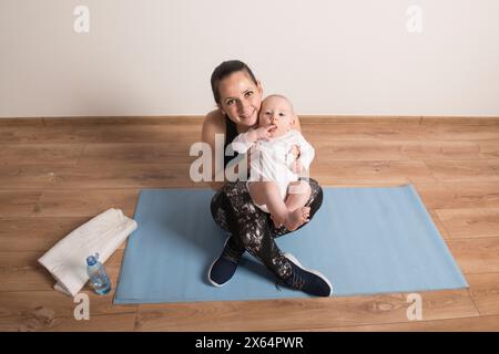 Heimtraining für Mutter und Baby, Mami und ich trainieren. Körperliche Aktivität der Mutter während der Bindung mit Kindern. Stockfoto