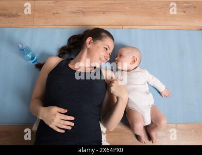 Heimtraining für Mutter und Baby, Mami und ich trainieren. Körperliche Aktivität der Mutter während der Bindung mit Kindern. Stockfoto