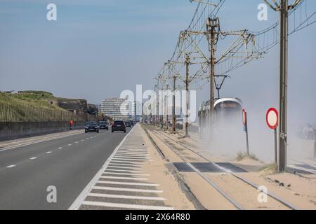 Die Küstenstraßenebahn Kusttram - de Lijn galt lange als die längste Straßenbahn Linie der Welt. Zwischen Knokke und de Panne befährt sie die gesamte Küste Belgiens. Hier in Raversijde zwischen Middelkerke und Oostende fährt die Bahn zwischen den Bunkern und Geschützen des ehemaligen Atlantikwalls und dem Strand. Im Hintergrund das markante Gebäude des Casino Middelkerke 12.05.2024 Oostende Raversijde Westflandern Belgien *** die Küstenstraßenbahn Kusttram de Lijn galt lange als die längste Straßenbahnlinie der Welt zwischen Knokke und de Panne, sie verläuft hier entlang der gesamten belgischen Küste Stockfoto