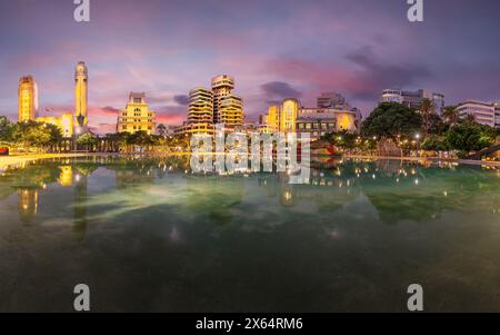 Die Dämmerung steigt auf der Plaza de Espana, Santa Cruz de Tenerife, mit atemberaubenden Reflexionen und Stadtlichtern, die eine fesselnde urbane Szene schaffen. Stockfoto