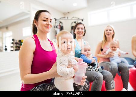 Bewegungsklasse für Babys. Eltern helfen Babys, die motorischen Fähigkeiten zu verbessern, die richtige Bewegung auf dem Fitball. Pädiatrische Physiotherapeutin, Führungsgruppenübung c Stockfoto