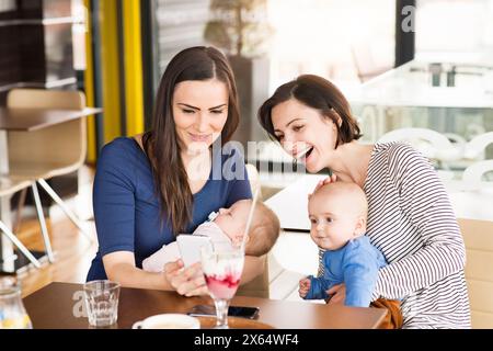 Neue Mom-Freunde gehen mit Babys ins Café. Gemeinsame Freizeit während des Mutterschaftsurlaubs in der Stadt. Stockfoto