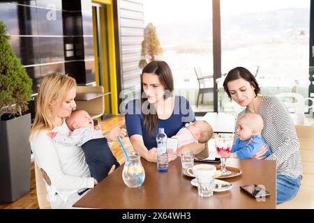 Neue Mom-Freunde gehen mit Babys ins Café. Gemeinsame Freizeit während des Mutterschaftsurlaubs in der Stadt. Stockfoto