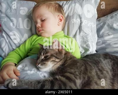 Innocent Bonding: Ein kleiner Junge fängt die Unschuld der Kindheit ein. Er umarmt und küsst eine rote Katze und bildet eine entzückende Bindung im Komfort o Stockfoto