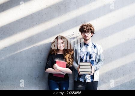 Junge Universitätsstudenten, die einen Stapel Bücher halten, sich auf die Abschlussprüfung vorbereiten. Studiengruppe. Stockfoto