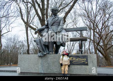 Süßer kleiner Junge in grünen Gummistiefeln füttert Tauben von der Bank. Bild mit Tonung und selektivem Fokus. Ein Junge füttert Tauben im Park. Hoch Stockfoto