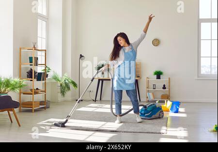 Frau tanzt mit Vakuum durch die Hausarbeit Stockfoto