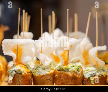 Typischer Snack aus dem Baskenland, Pinchos oder Pinxtospieße mit kleinen Brotstücken, Meeresfrüchten, Eiern und Käse in der Bar in Bilbao, Spanien. Stockfoto