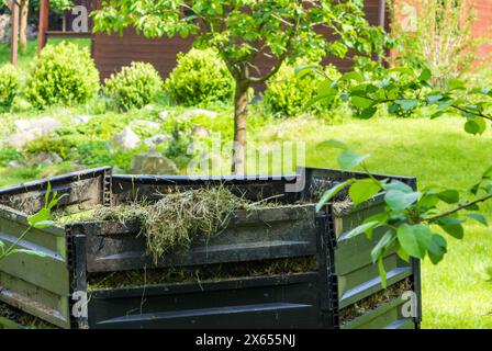 Schichten von verrottendem Kompost in Kunststoff-Kompostereimer im Frühlingsgarten im Dorf Stockfoto