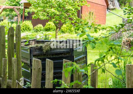 Schichten von verrottendem Kompost in Kunststoff-Kompostereimer im Frühlingsgarten im Dorf Stockfoto