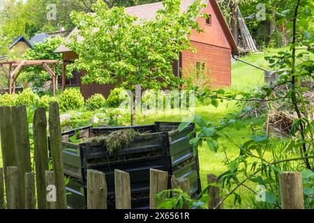 Schichten von verrottendem Kompost in Kunststoff-Kompostereimer im Frühlingsgarten im Dorf Stockfoto