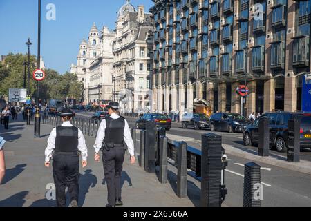 Weibliche Metropolitanpolizisten patrouillieren zu Fuß gegenüber dem Portcullis House in Westminster London am sonnigen Tag, Polizei patrouilliert durch die Straßen, London, England Stockfoto