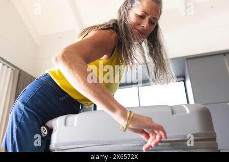 Zu Hause öffnet die kaukasische reife Frau den Koffer Stockfoto