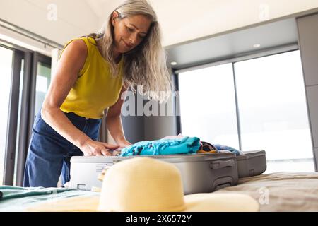 Zu Hause, reife kaukasierin mit langen grauen Haaren, Koffer packen Stockfoto