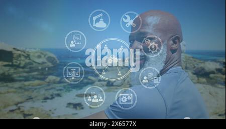 Bild von Medienikonen über lächelndem afroamerikaner am Strand Stockfoto