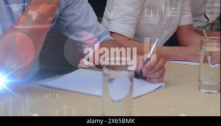 Eine Person mit rosa Hemd, die auf Papier schreibt, eine andere mit weißen, hochkrempelnden Ärmeln Stockfoto