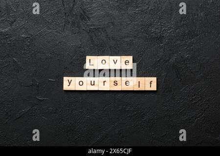 Liebe dich selbst Wort auf Holzblock geschrieben. Love Yourself Text auf Zementtisch für Ihr Design, Draufsicht Konzept. Stockfoto