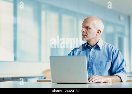 Ältere Geschäftsleute arbeiten fleißig in einem Büro mit Blick auf einen belebten Hafen, das eine Mischung aus Technologie und Ruhe bietet Stockfoto