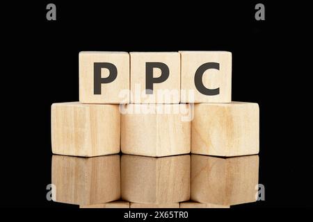 Concept Business. PPC – Text zum Bezahlen per Klick auf Holzwürfel auf schwarzem Hintergrund Stockfoto