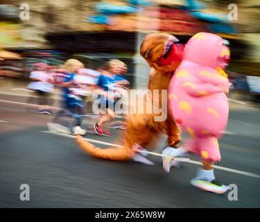 Bewegungsunschärfe des Dinosauriers und Mr. Blobby im Blackpool 10 K Fun Run entlang der Promenade Stockfoto