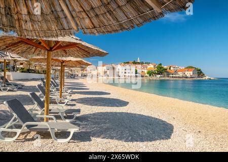 Ein leerer Strand mit Sonnenschirmen und leerstehenden Liegen am Primosten Strand, Kroatien Stockfoto