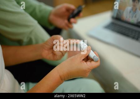 Reife Frau, die den Blutzucker mit einem Glukometer überprüft, während sie mit einem Arzt telefoniert Stockfoto