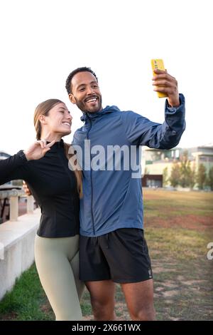 Glückliches junges Paar, das ein Selfie mit dem Smartphone macht, das bereit ist, zu trainieren. Stockfoto