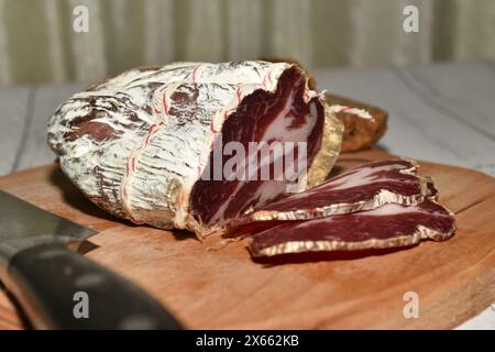 Geschnittenes roh geräuchertes coppa-Fleisch liegt auf einem Schneidebrett, Seitenansicht. Stockfoto