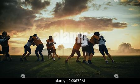 American Football Field zwei Teams konkurrieren: Spieler bestehen und laufen angreifend, um Touchdown-Punkte zu erzielen. Profisportler kämpfen um den Ball, Tackle. Dramatische Goldene Stunde Stockfoto