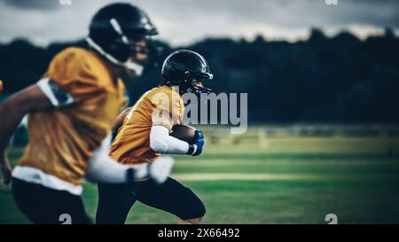 American Football Field zwei Teams konkurrieren: Erfolgreicher Spieler läuft um Touchdown-Punkte. Professionelle Athleten kämpfen um den Ball, Tackle, kämpfe um den Meisterschaftssieg. Stockfoto