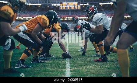 American Football Championship. Teams bereit: Professionelle Spieler, aggressiv gegeneinander, bereit zum Pushen, Tackling. Wettbewerb voller brutaler Energie, Macht. Stadionaufnahme mit dramatischem Licht Stockfoto