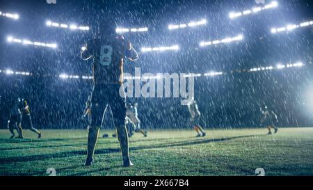 American Football Teams treten an: Substitution Athlete Warrior steht auf dem Stadion Field bereit, um das Spiel zu gewinnen. Spieler laufen, angreifen, um Touchdown zu erzielen. Regnerische Nacht mit dramatischem Nebel Stockfoto