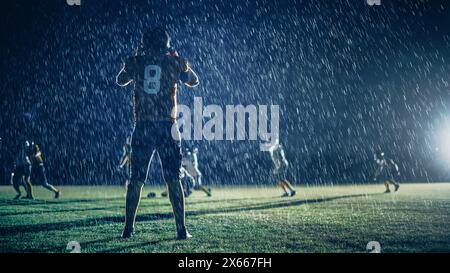 American Football Teams treten an: Substitution Athlete Warrior steht auf dem Feld bereit, um das Spiel zu gewinnen. Spieler laufen, angreifen, um Touchdown zu erzielen. Regnerische Nacht mit dramatischem Nebel Stockfoto