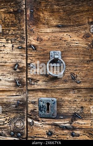 Alte Holztür mit Schlössern eines cimbrischen Gebäudes im cimbrischen Dorf Zamberlini. Bosco Chiesanuova, Lessinia, Veneto, Italien. Stockfoto