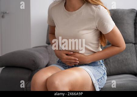 Obstipation. Junge Frau mit starken Bauchschmerzen, die zu Hause auf dem Sofa sitzt. Stockfoto