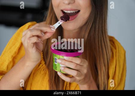 Unwiedererkennbares schönes Mädchen, das zu Hause Acai Sorbet Eis Eis gefrorenen Dessert isst Stockfoto