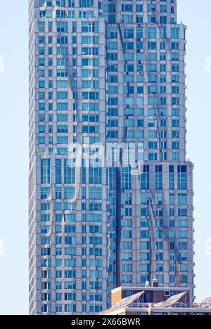 Fassadendetail der 8 Spruce Street, früher bekannt als New York von Gehry, einem mit Edelstahl verkleideten Wohnturm in Lower Manhattan. Stockfoto